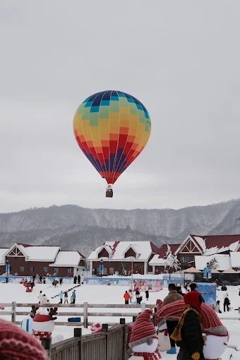 Rainbow hot-air balloon floating over a snow village